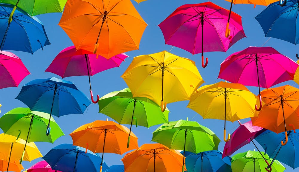 Identical multi-colored umbrellas floating in the air